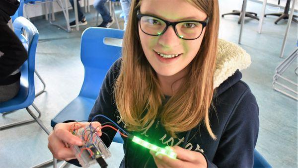 Girl learning coding and electronics holding up her creation