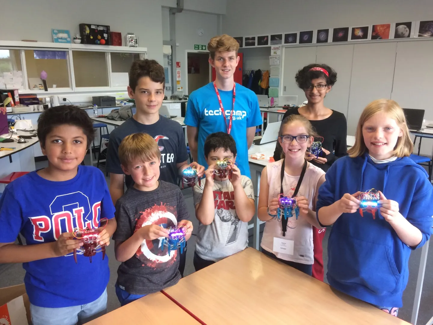 Children and tutor at Tech Camp holding up robots they have built